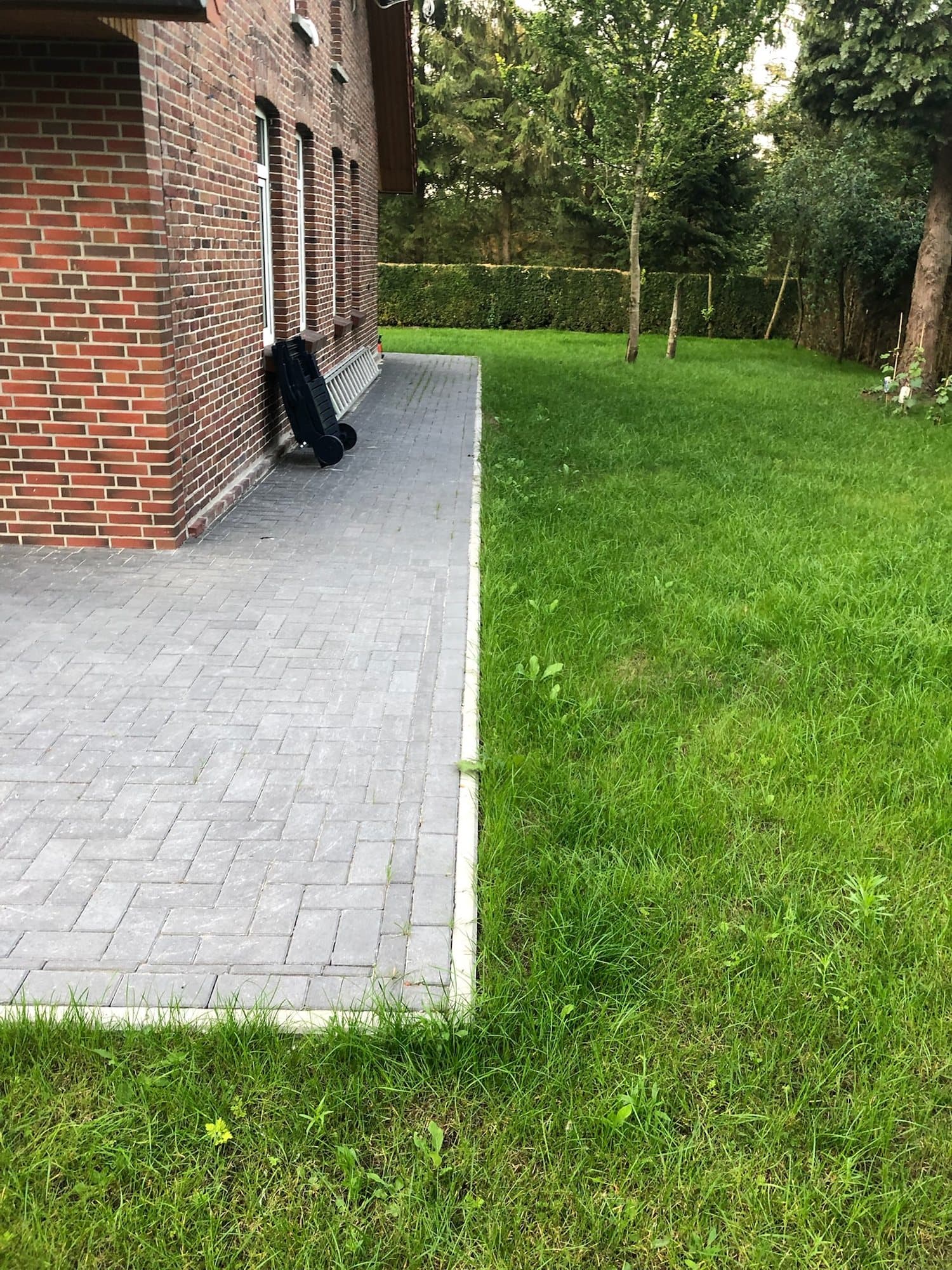 Gepflasterter Weg mit Rasen entlang des Backsteinhauses