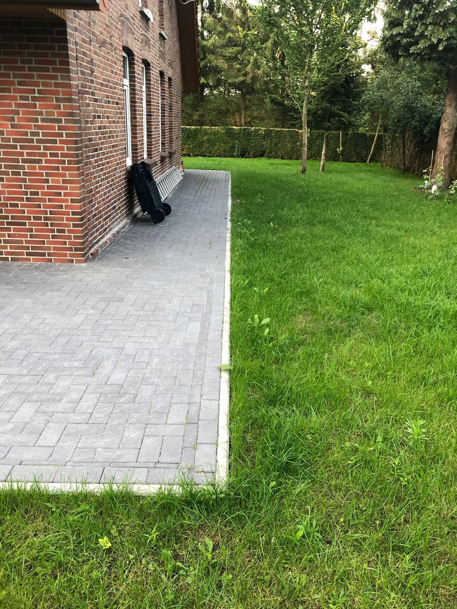 Gepflasterter Weg mit Rasen entlang des Backsteinhauses