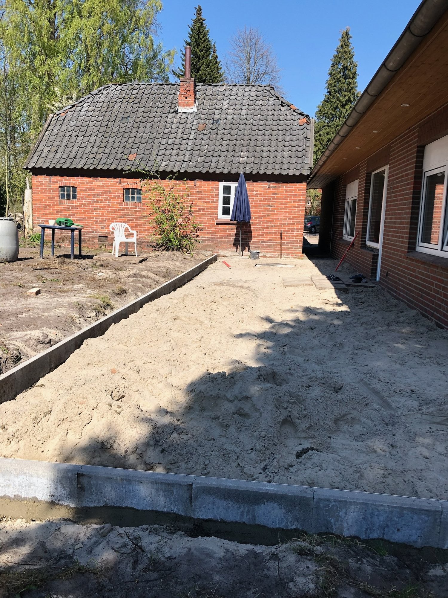 Sandfläche mit Randsteinen zwischen zwei Gebäuden