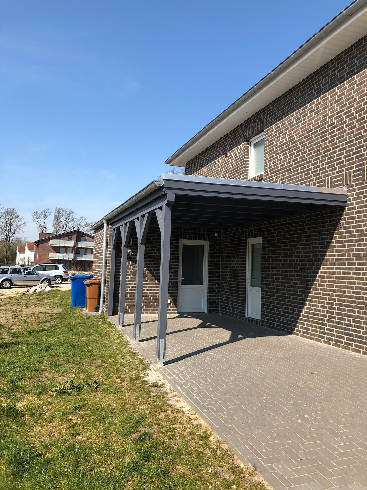 Terrassenüberdachung mit Pflasterfläche an einem Klinkerhaus