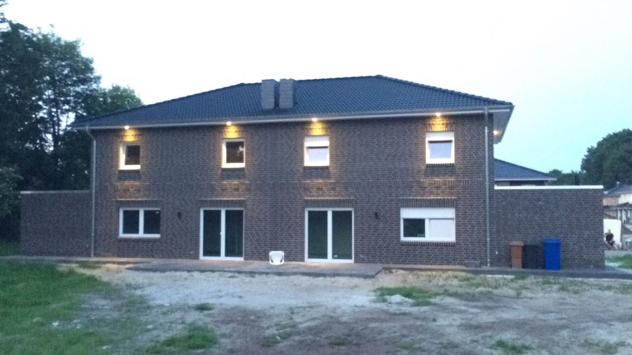 Fertiges Mehrfamilienhaus mit Klinkerfassade und Außenbeleuchtung